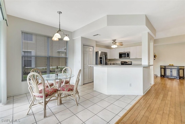 kitchen with a ceiling fan, a peninsula, stainless steel appliances, light countertops, and white cabinetry