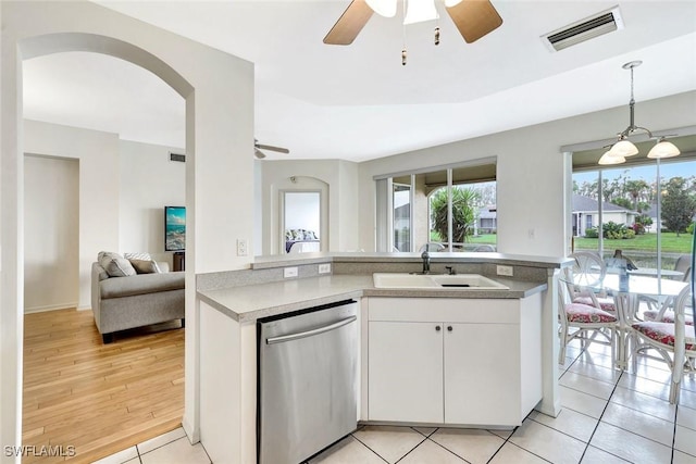 kitchen with visible vents, white cabinets, open floor plan, stainless steel dishwasher, and a sink