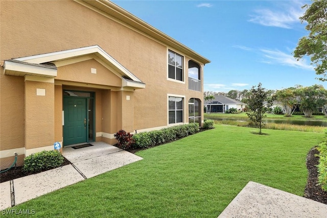 entrance to property with a lawn and stucco siding