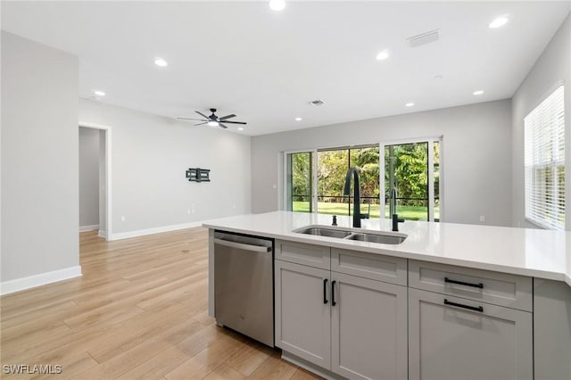 kitchen featuring a sink, light wood finished floors, light countertops, and stainless steel dishwasher