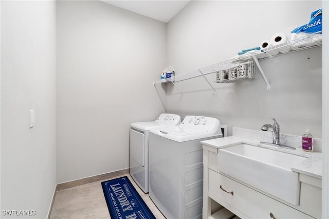 clothes washing area featuring light tile patterned floors, washing machine and dryer, laundry area, a sink, and baseboards