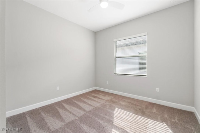 carpeted spare room featuring a ceiling fan and baseboards