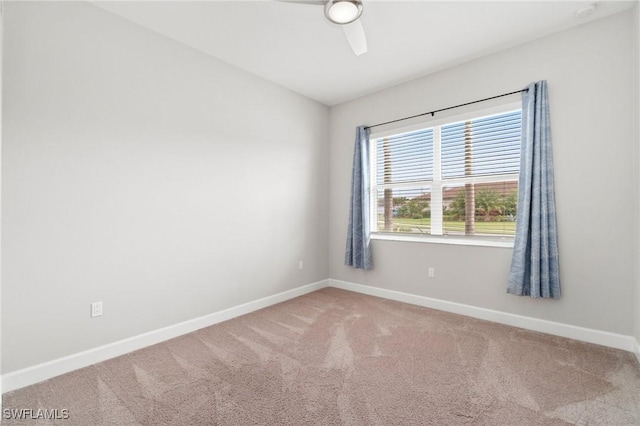 carpeted spare room featuring ceiling fan and baseboards