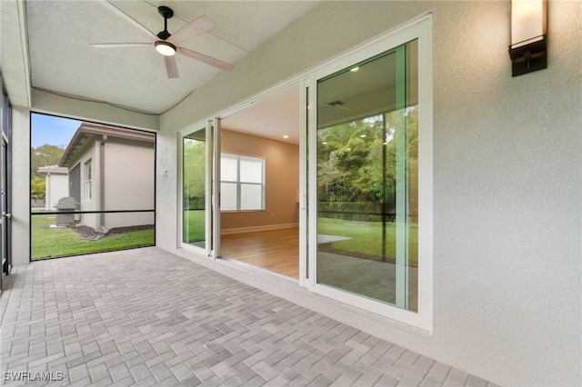 unfurnished sunroom featuring ceiling fan and a wealth of natural light