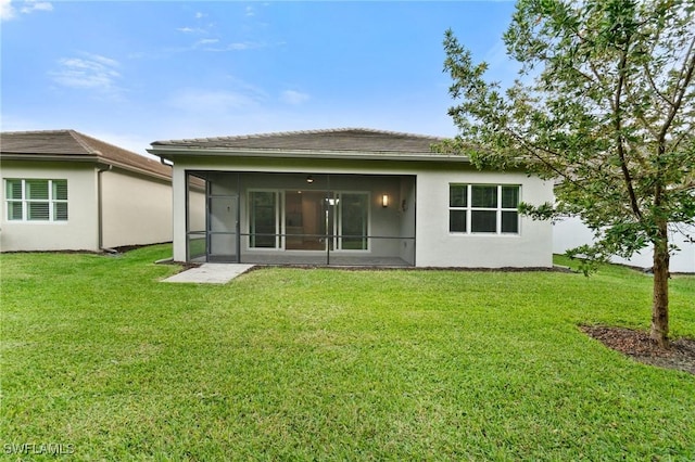 back of property with a yard, a sunroom, and stucco siding