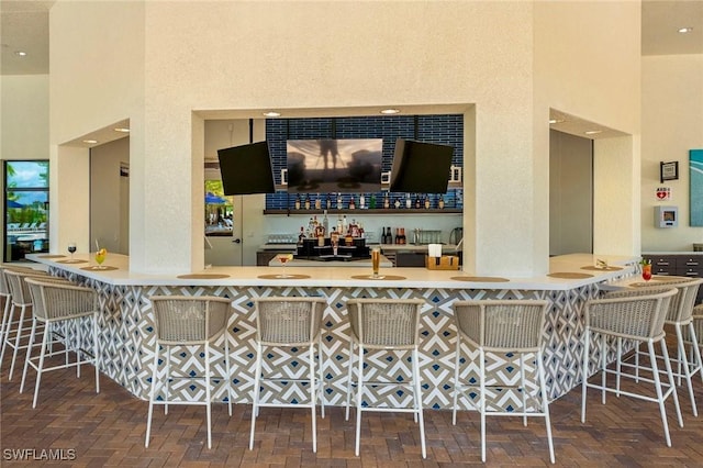 bar with a high ceiling, brick floor, and a dry bar