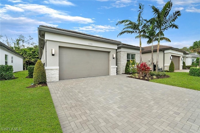 view of front of home featuring a garage, stone siding, decorative driveway, a front yard, and stucco siding