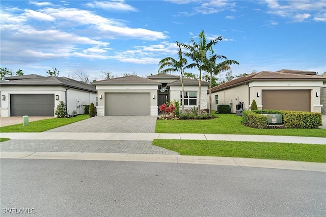 view of front of home with a front yard, decorative driveway, an attached garage, and stucco siding