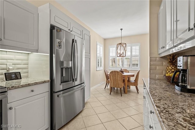 kitchen with stainless steel fridge, white cabinets, light tile patterned floors, decorative backsplash, and light stone countertops