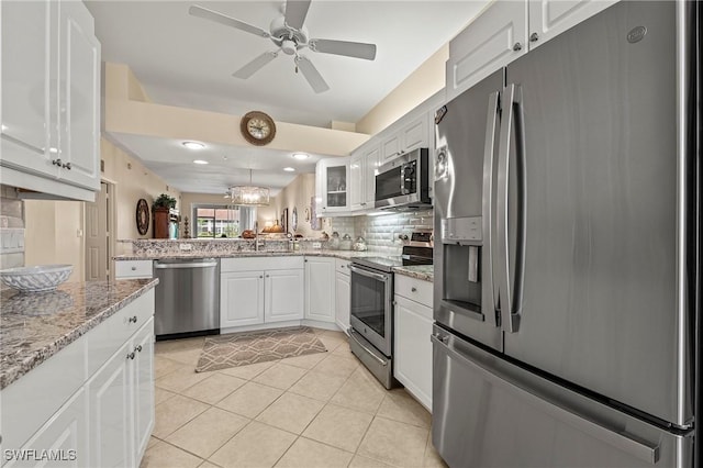 kitchen with a sink, tasteful backsplash, white cabinetry, stainless steel appliances, and light tile patterned flooring