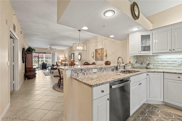 kitchen featuring a sink, stainless steel dishwasher, open floor plan, a peninsula, and light tile patterned floors