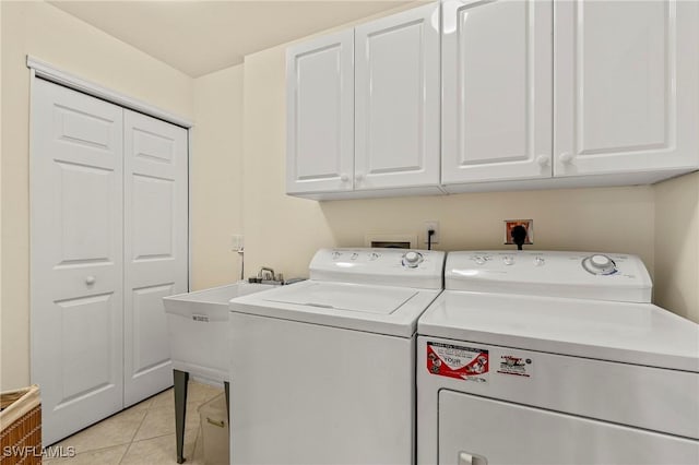 washroom featuring cabinet space, light tile patterned floors, and washer and dryer