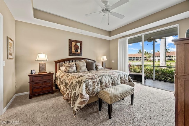 bedroom featuring light carpet, a tray ceiling, baseboards, and access to outside