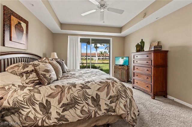 bedroom featuring light carpet, a raised ceiling, baseboards, and access to exterior