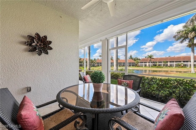 sunroom / solarium featuring a ceiling fan and a water view