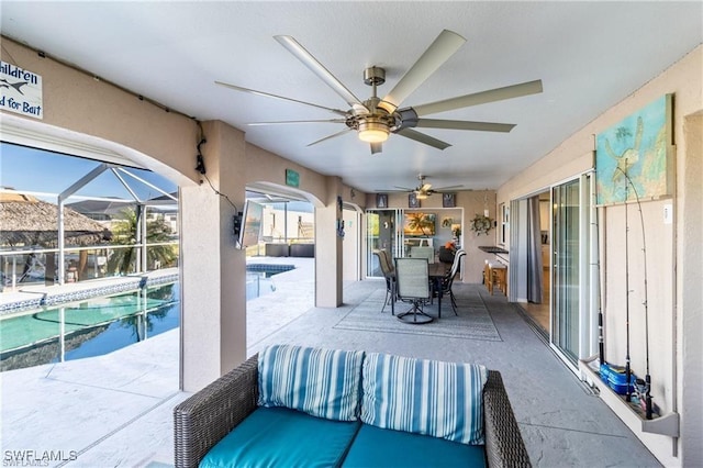 view of patio / terrace with glass enclosure, outdoor dining area, a ceiling fan, and an outdoor pool