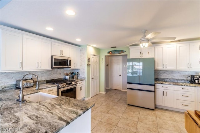 kitchen with stainless steel appliances, white cabinets, a sink, and light tile patterned floors