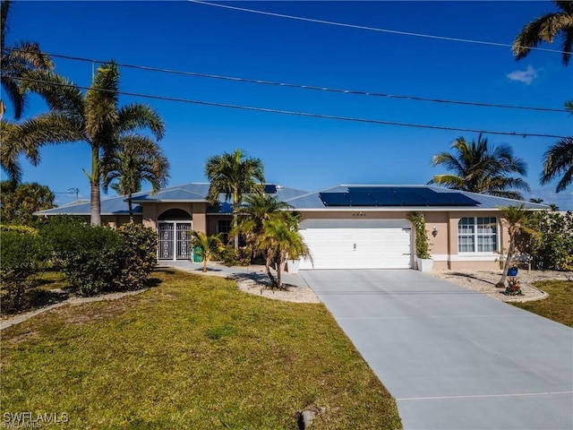 ranch-style home with an attached garage, solar panels, concrete driveway, stucco siding, and a front yard