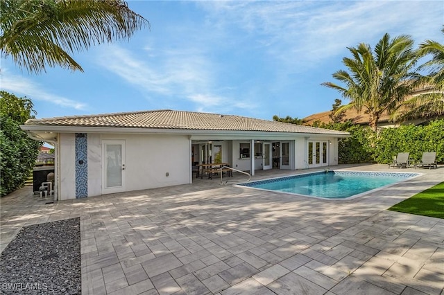 outdoor pool with french doors and a patio area