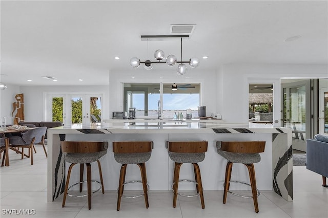 kitchen with french doors, light countertops, hanging light fixtures, and a kitchen bar