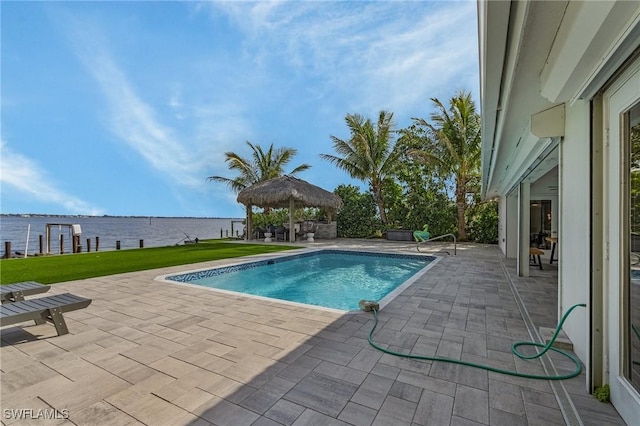 pool featuring a patio, a lawn, and a water view