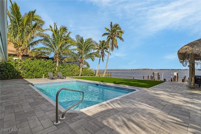 pool featuring a water view, a patio, and a lawn