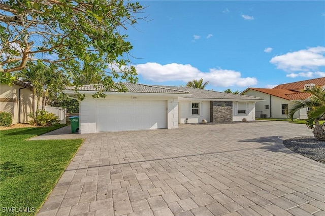 ranch-style home with a garage, decorative driveway, a tile roof, and a front lawn