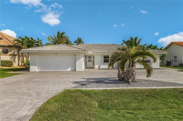 single story home with a front lawn, decorative driveway, an attached garage, and a tile roof