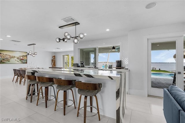 kitchen featuring a large island, visible vents, a breakfast bar, and light tile patterned flooring