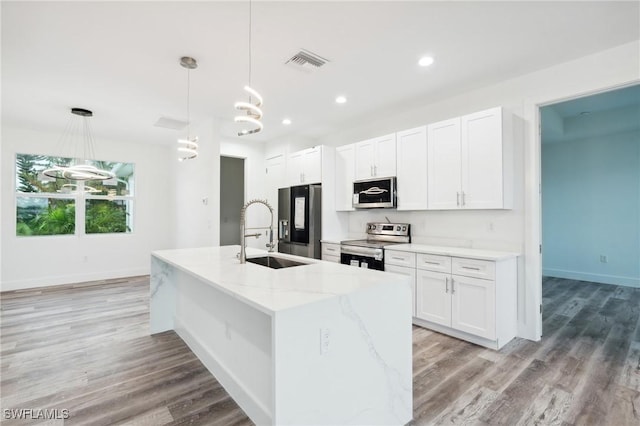 kitchen with a center island with sink, visible vents, white cabinets, appliances with stainless steel finishes, and a sink