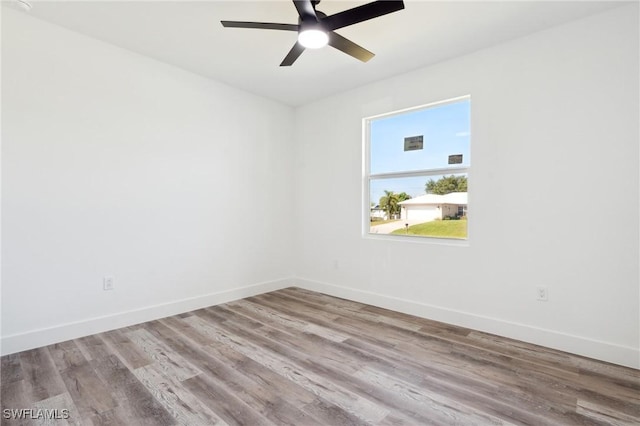 unfurnished room with wood finished floors, a ceiling fan, and baseboards