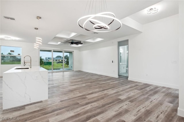 unfurnished room featuring coffered ceiling, a sink, baseboards, and wood finished floors