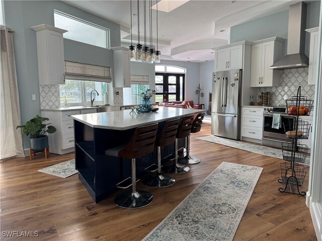 kitchen featuring a kitchen island, wall chimney range hood, dark wood-style floors, and stainless steel appliances