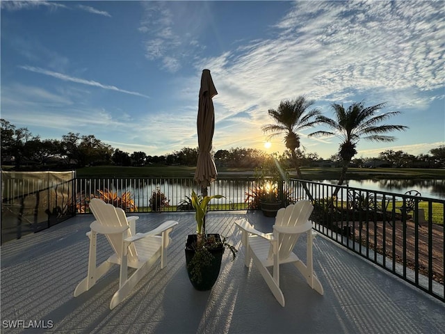 deck at dusk featuring a water view