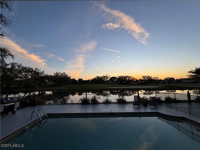 view of swimming pool featuring fence and a water view