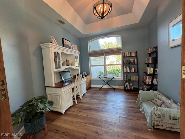 office space with baseboards, a chandelier, dark wood-type flooring, visible vents, and a raised ceiling