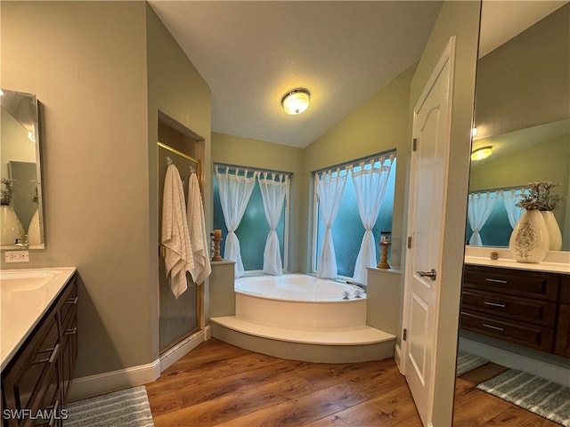 bathroom with a bath, vanity, vaulted ceiling, wood finished floors, and a stall shower
