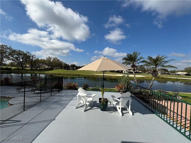 view of patio featuring a water view and fence