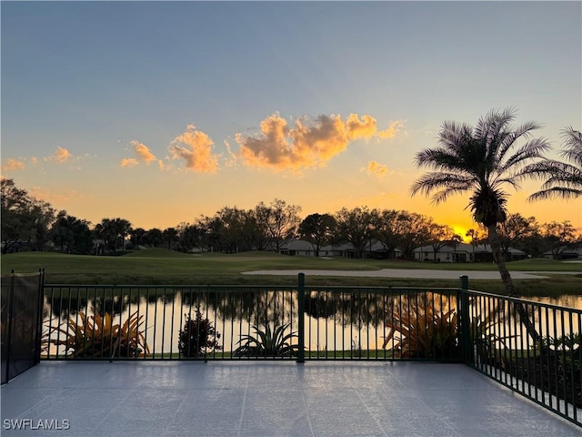 patio terrace at dusk with a water view and a yard