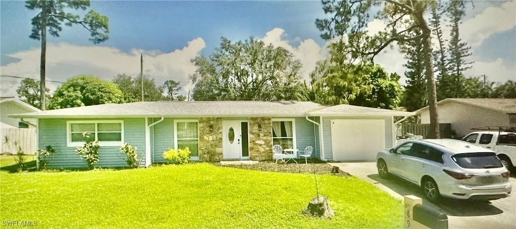 ranch-style house featuring a front yard, concrete driveway, fence, and an attached garage