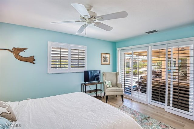 bedroom with access to exterior, visible vents, a ceiling fan, and wood finished floors