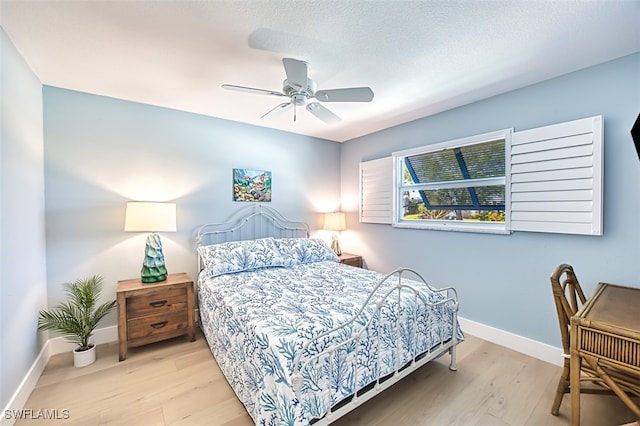 bedroom featuring a textured ceiling, wood finished floors, baseboards, and ceiling fan