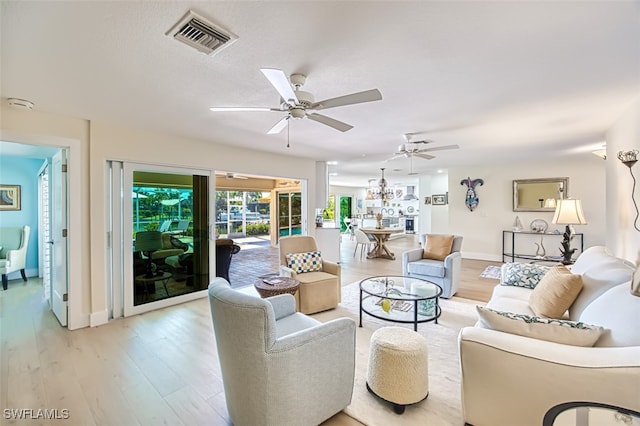 living area featuring visible vents, ceiling fan, baseboards, and light wood-style floors