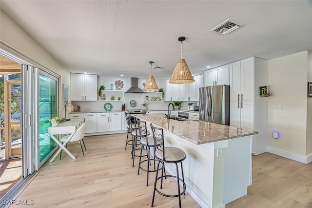 kitchen with visible vents, open shelves, a sink, stainless steel appliances, and wall chimney exhaust hood