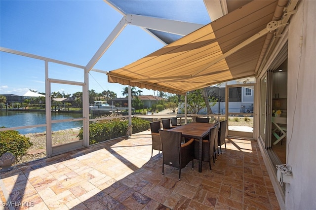 view of patio with glass enclosure, outdoor dining space, and a water view