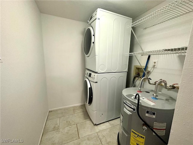 laundry area featuring laundry area, light tile patterned floors, stacked washer and dryer, baseboards, and water heater