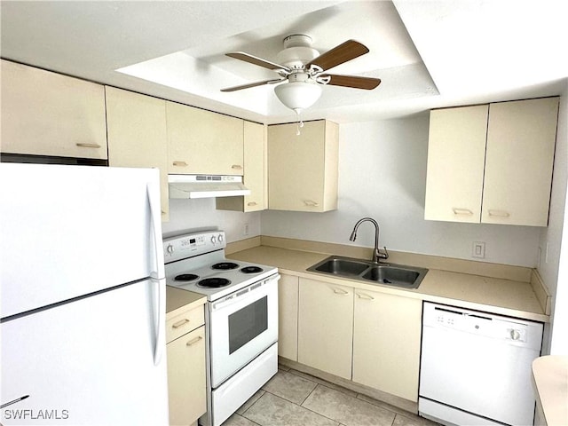 kitchen with cream cabinetry, light countertops, a sink, white appliances, and under cabinet range hood