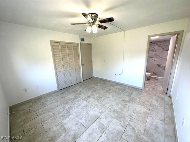 unfurnished bedroom featuring ensuite bathroom, a closet, visible vents, and a ceiling fan