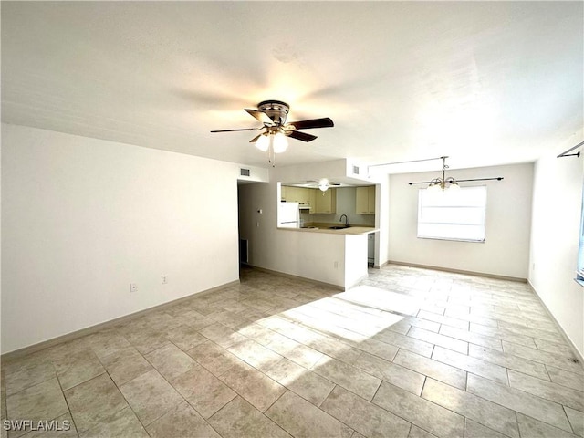 unfurnished living room with visible vents, a sink, baseboards, and ceiling fan with notable chandelier