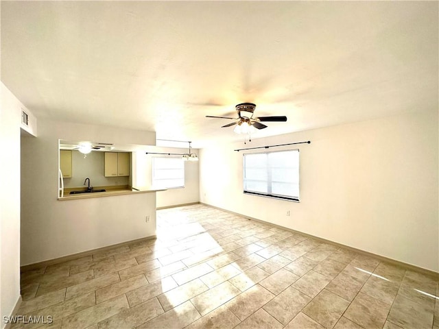 spare room featuring a ceiling fan, visible vents, a sink, and baseboards